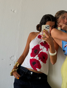 A women capture a selfie, smiling, in front of a clean white wall.