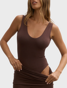 A model poses in a brown dress with a v neckline, emphasizing its chic silhouette.