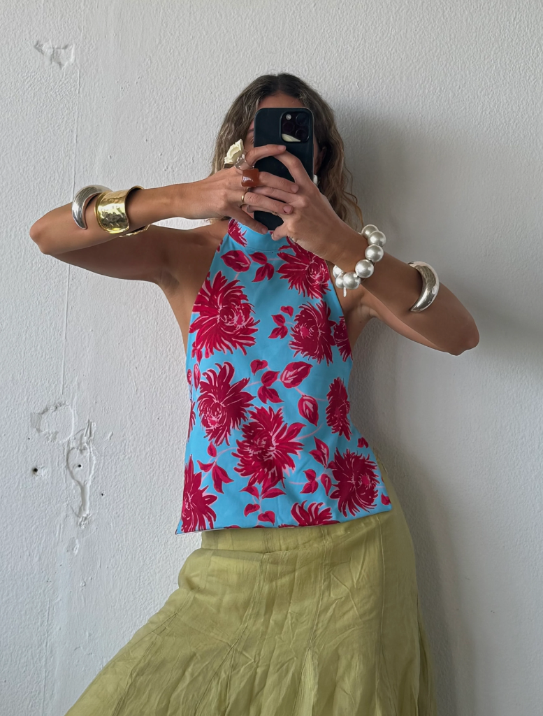 A woman poses for a selfie against a simple white wall background.