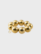A gold bracelet featuring a prominent large ball as its centerpiece.