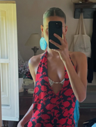 A woman dressed in red and black stands on a stone wall, creating a bold visual contrast with the surrounding landscape.