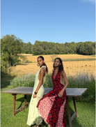A woman wearing a red and black dress poses on a stone wall, highlighting her fashion choice in an outdoor setting.