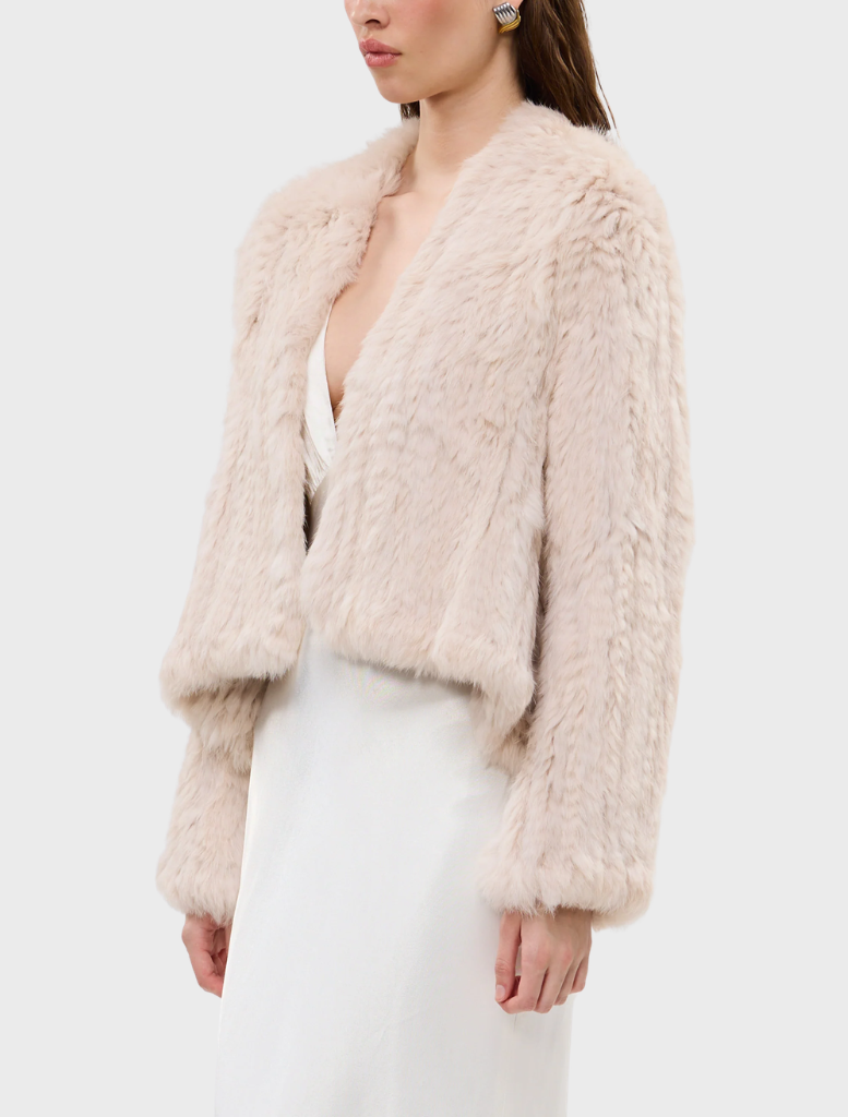 A stylish stone Emma fur jacket draped on a hanger, highlighting its luxurious fabric and modern silhouette.