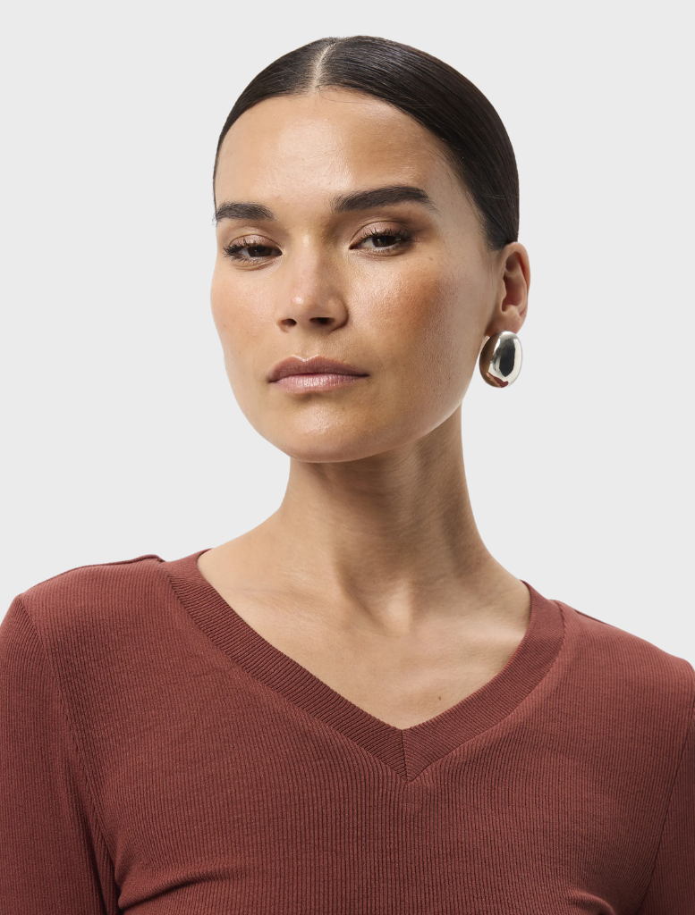 A rust-colored Sedona Top draped on a chair, emphasizing its relaxed style and short sleeves for everyday use.