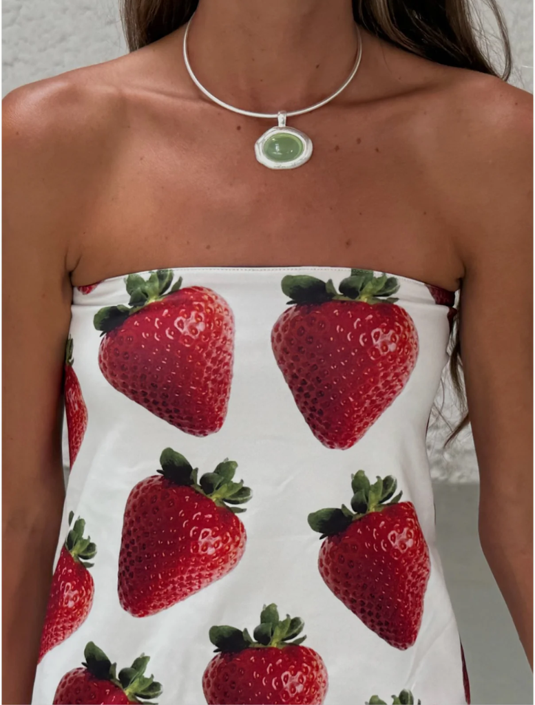 A woman models a strawberry print Top showcasing a vibrant and playful fashion choice.
