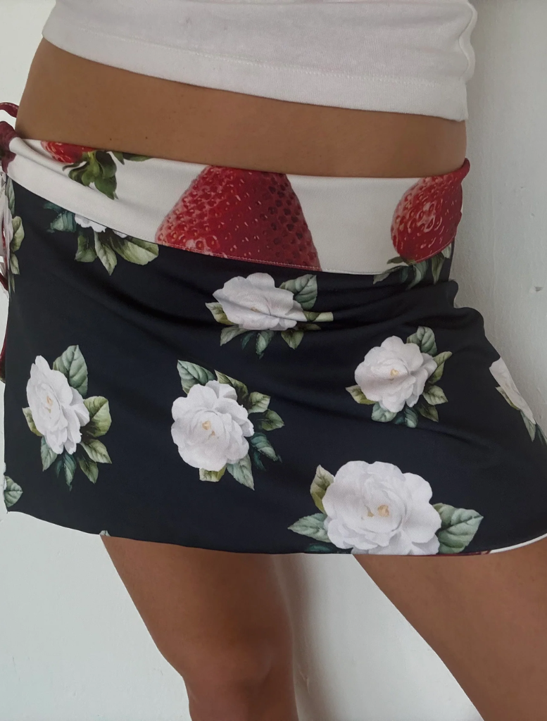 A woman models a white flower, showcasing a vibrant and playful fashion choice.