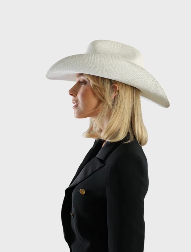 A white Addison Cowboy hat resting on a rustic table, highlighting its traditional western style and craftsmanship.