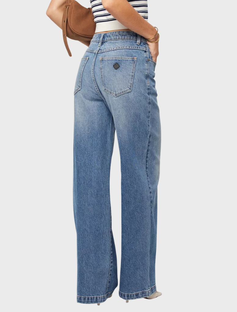 A woman models wide-legged jeans paired with a striped top, embodying a relaxed and fashionable look.