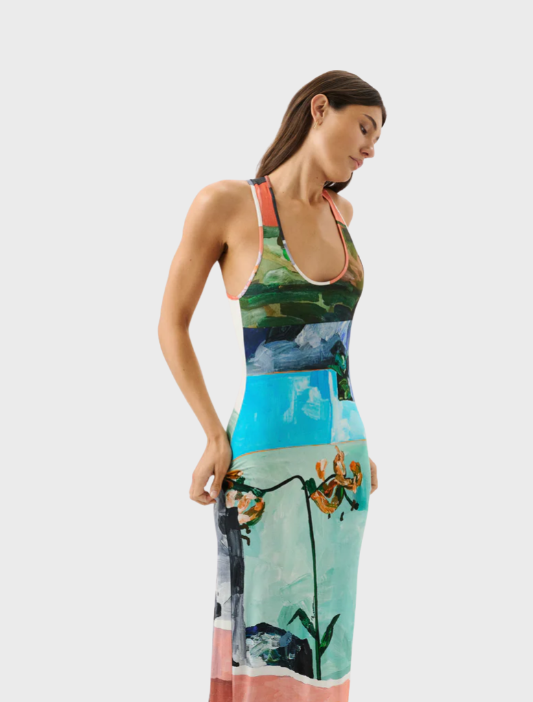 A woman showcases a colorful dress decorated with flowers, reflecting a bright and cheerful fashion choice.