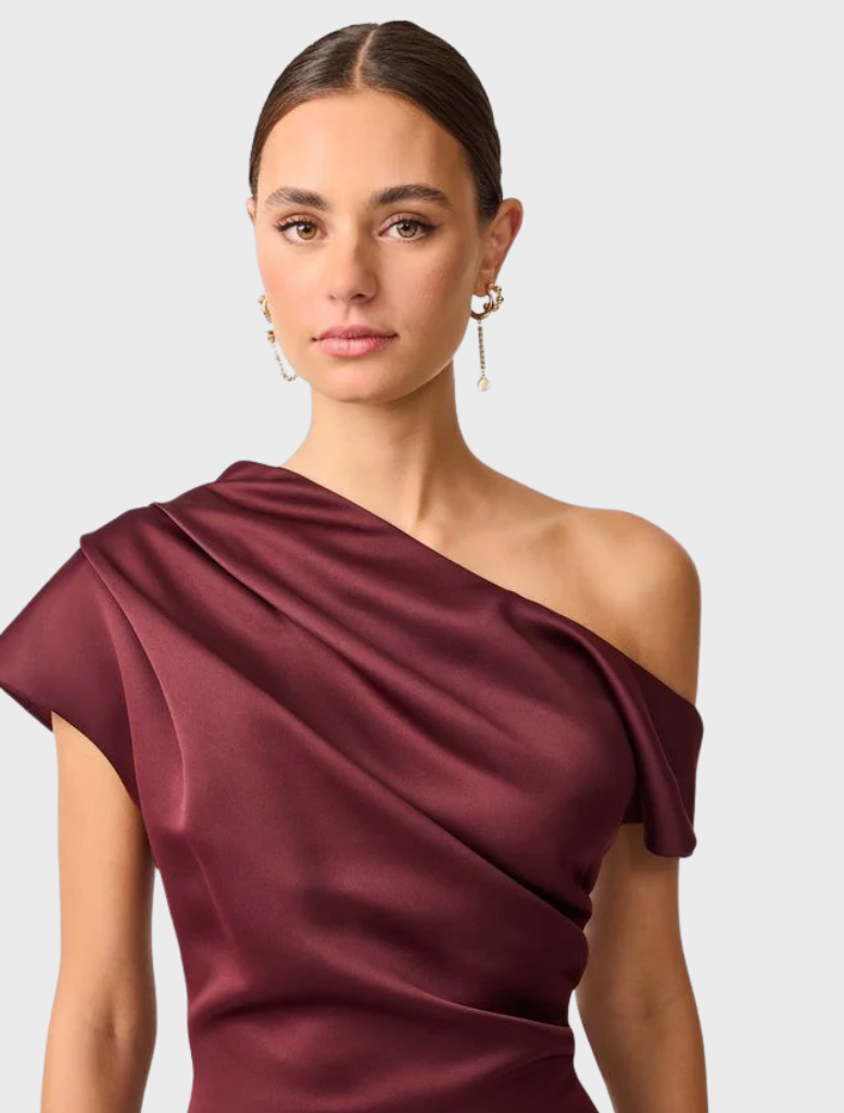 The berry satin Livia Gown features an asymmetric hem, combining elegance with contemporary design.