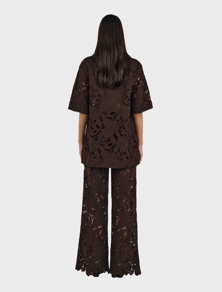 A woman in a black top and brown Lotus Lace pants, highlighting a chic fashion choice.