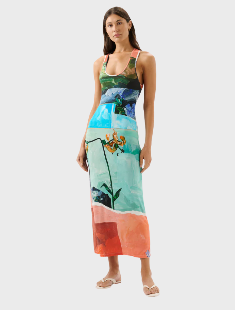 A woman models a bright dress adorned with colorful flowers, highlighting her cheerful style.
