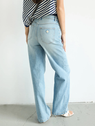 A woman dressed in wide-legged jeans and a striped top, featuring the 94 High & Wide collection by Jody Blue.
