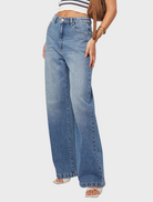 A woman dressed in wide-legged jeans and a striped top poses, highlighting a trendy and comfortable ensemble.