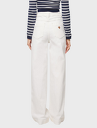 Model in white wide-leg pants and a striped crop top, showcasing a stylish summer outfit.
