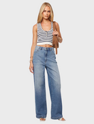 A woman in wide-legged jeans and a striped top stands confidently, showcasing a casual yet stylish outfit.