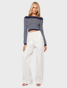 Model in white wide-leg pants and a striped crop top, showcasing a stylish and casual summer outfit.