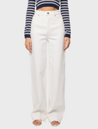 A model displays a chic outfit featuring white wide-leg pants and a striped crop top, perfect for warm weather.