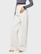 Fashion model wearing white wide-leg pants paired with a striped crop top, exuding a trendy look.