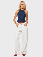 A model showcases a blue top paired with white wide-leg pants, highlighting a stylish and casual outfit.