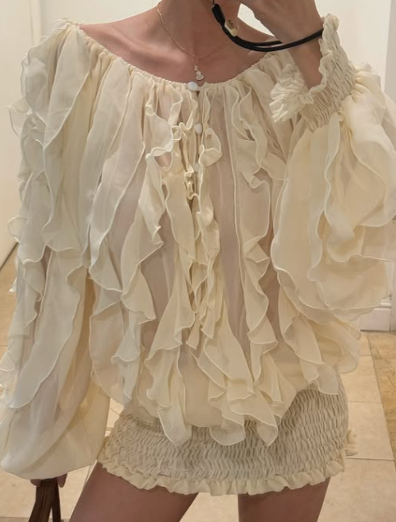 Cream-colored ruffled blouse and dress with long sleeves on a neutral background