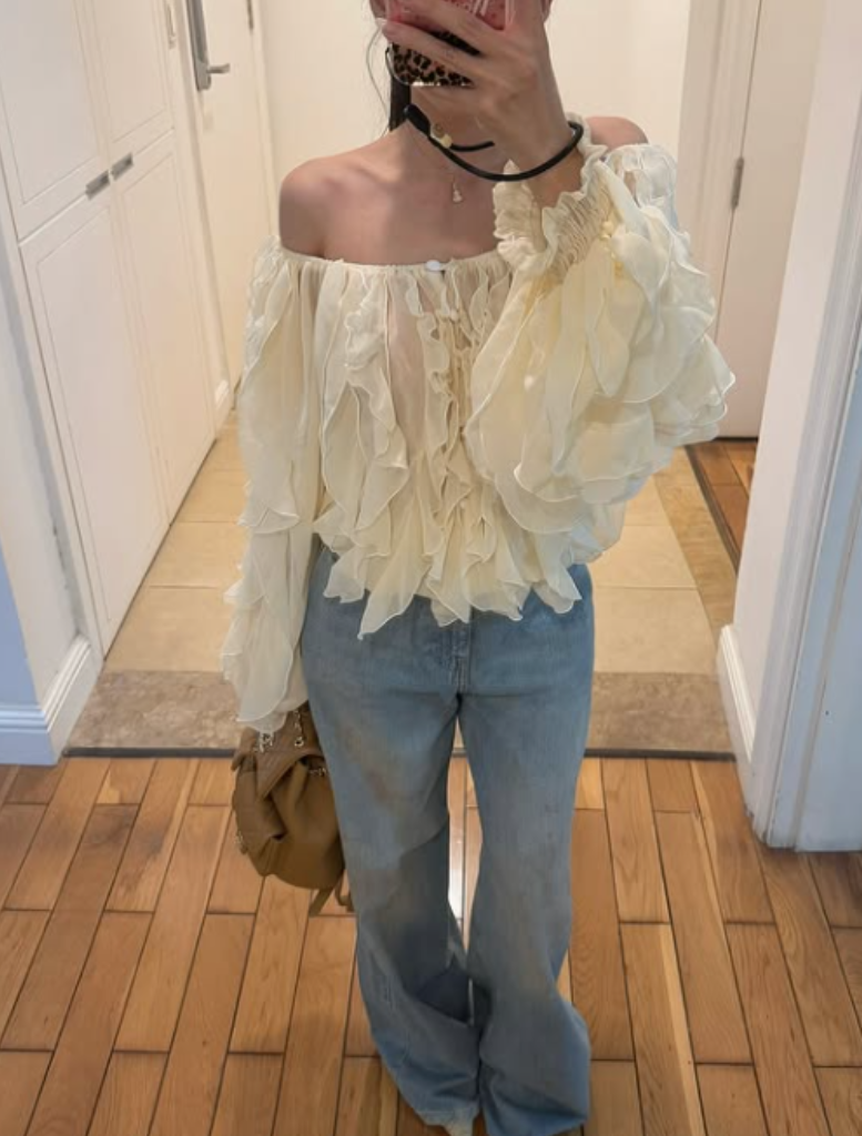 Cream-colored ruffled blouse and dress with long sleeves on a neutral background