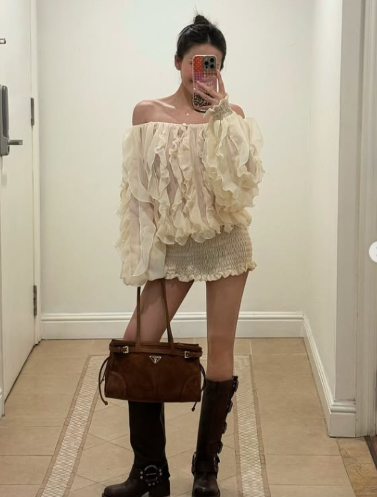 Cream-colored ruffled blouse and dress with long sleeves on a neutral background