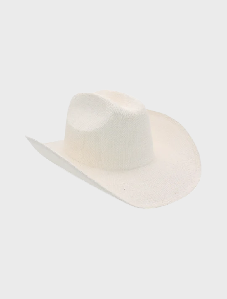 A white Addison Cowboy hat resting on a rustic table, highlighting its traditional cowboy aesthetic.