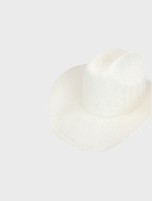 White Addison Cowboy hat positioned on a wooden background, emphasizing its iconic western look and elegant design.