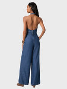 This jumpsuit combines a retro halter-neck style with a wide-leg cut, crafted from soft, lightweight denim for comfort.