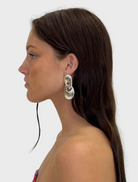 Two circular silver earrings, showcasing a modern and minimalist design for versatile wear.