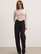 Model in black wide-leg pants paired with a pink ballet-lila bodysuit, showcasing a stylish and modern outfit.