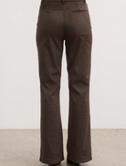 The model is dressed in brown pants paired with a matching top, showcasing a stylish outfit.