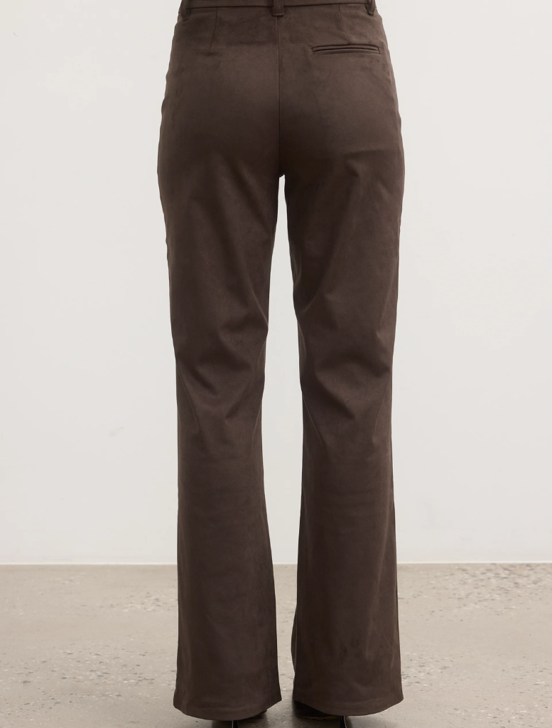 The model is dressed in brown pants paired with a matching top, showcasing a stylish outfit.