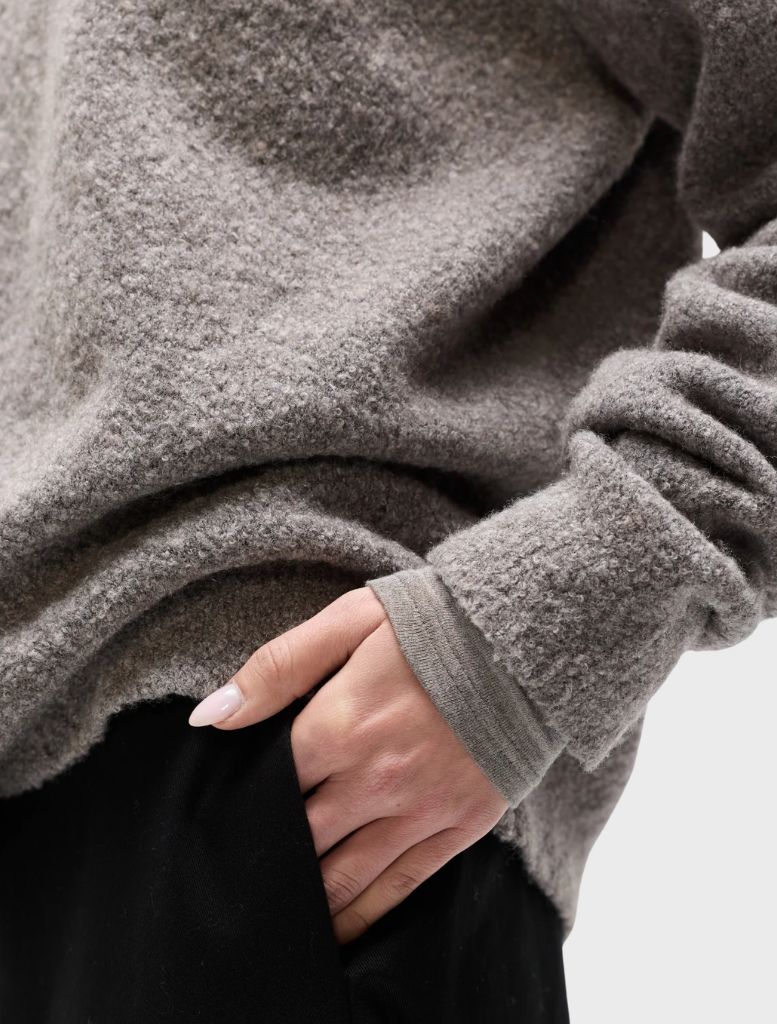 Stella crew neck sweater in beige grey color, showcased on a hanger with a simple backdrop.