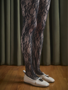 A pair of black Flora Tights laid flat, highlighting their smooth material and stylish appearance.
