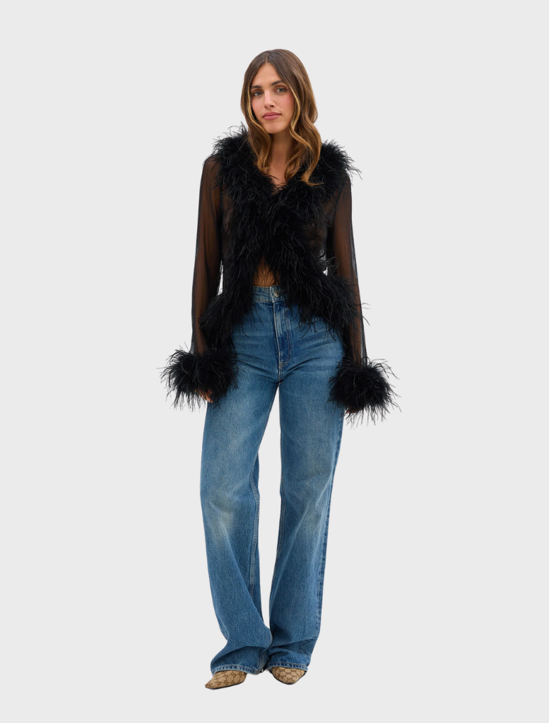 A model showcases the black Gigi Feather Blouse, featuring decorative feathers for a chic and fashionable look.