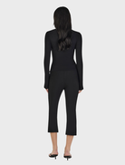 Black Nina Cardi Top draped elegantly, showcasing its modern cut and fabric texture ideal for layering outfits.