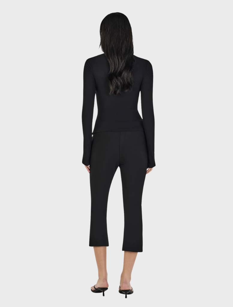 Black Nina Cardi Top draped elegantly, showcasing its modern cut and fabric texture ideal for layering outfits.