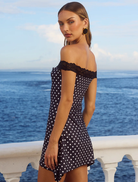 Stylish black mini dress featuring white polka dots, short sleeves, and a flattering fit for various events.
