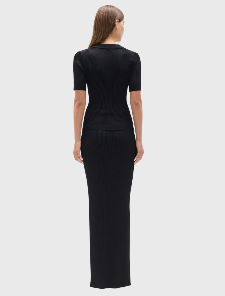 The Rhylin Skirt in black has a ribbed knit, wide waistband, belt loops, and a fitted silhouette that extends to maxi length.