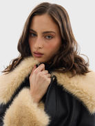 Stylish black Willow Jacket with leather-like finish, plush shearling, and oversized collar, perfect for layering in any season.