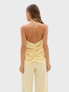 A model wears pale yellow Celeste Jean Pants along with a top, exemplifying a chic and trendy ensemble.