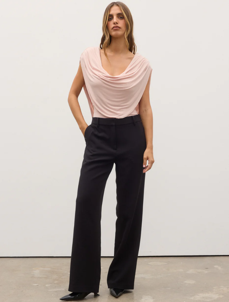 Model wearing a pink Flora Bodysuit and black pants, showcasing a stylish and modern outfit.