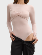 Back perspective of a woman dressed in a pink ballet-lila bodysuit, emphasizing the garment's elegant design.