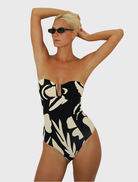 Chic bandeau one-piece with supportive bust, adjustable straps, and a sophisticated cream and black design, ideal for summer.