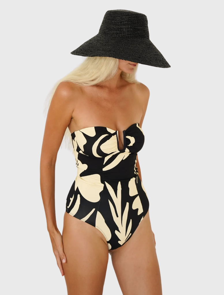Sculpted bandeau swimsuit with a plunging neckline, spliced seams, and full back coverage in a warm cream and black print.