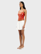 Elegant backless top in burnt orange with sequin detailing, offering a chic and eye-catching appearance.
