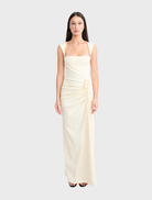The Samara gown in butter showcases a graceful design with a light, airy fabric perfect for formal occasions.