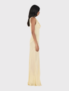 Palermo Gown in butter yellow, showcasing a draped cowl neck, twist strap details, and a comfortable bias-cut maxi skirt.